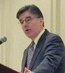 Man with glasses and tie at podium