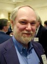 Man with beard, jacket and open shirt smiling