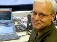 Ray smiling next to two laptops, one running Lotus Notes