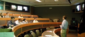 Students listening to professor with TV sets on wall