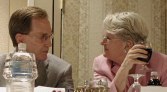 Two people at the head table facing each other while eating