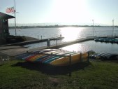 Sun setting over a body of water with kayaks on the bank