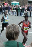 People behind barracades watching two women running a few feet apart