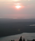 Sun setting with lakes visible and tree in foreground