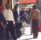 Person on Segway on street corner talking to one person while others ignore it