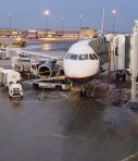 Looking out at a plane parked at the gate with no snow visible in the distance