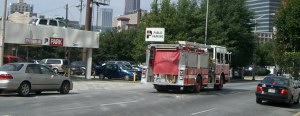 Wide one-way street with two car pulled over as a fire truck passes