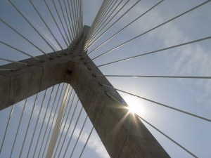 Looking up at inverted Y holding cables with sun peeking through