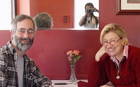 Two people smiling at the camera sitting at a restaurant table