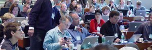 People sitting in a large class room with lots of open laptops