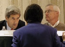 Kerry bending down sitting on podium to talk to Joyce with John next to him