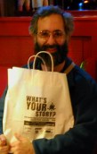 Dan holding bag labeled What's your story?